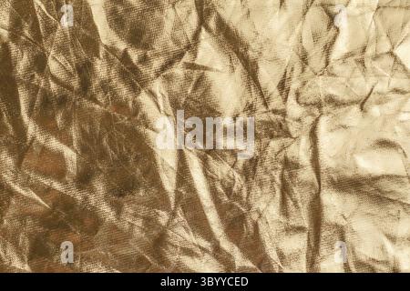 Zerknittertes, goldfarbenes Foliengewebe mit verblichener, verwaschener Textur. Abstrakter bunter Grunge-Hintergrund Stockfoto