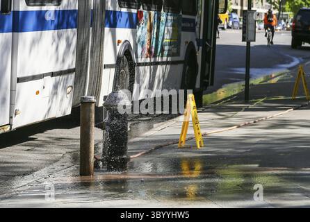 New York City, USA - 19. Mai 2014: Ein Bus hält vor einem offenen Hydranten. Schilder warnen vor einem nassen Boden, New York City, USA Stockfoto
