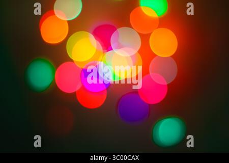 Hellrote, rosa, grüne und gelbe unscharfe Lichter über Schwarz. Lebhafte Stimmung für festliche Urlaubs- oder Nachtleben. Stockfoto