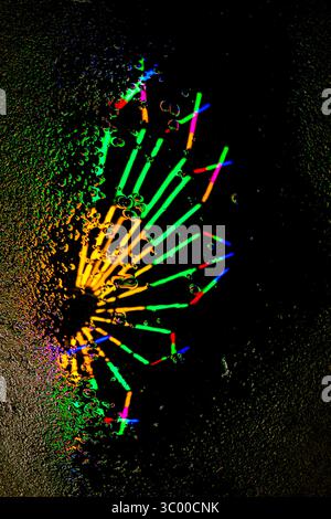 Festliche Lichter in Rot, Grün, Gelb, Blau reflektieren auf nassem Untergrund. Abstraktes vertikales Bild, perfekt für Nachtferien oder farbenfrohe Reiseszenen. Stockfoto