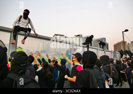 1. Dezember 2019, Hongkong, Volksrepublik China: Hongkong, China. Dezember 2019. Tausende demokratischer Demonstranten nehmen an dem friedlichen marsch von Tsim Sha Tsui nach Hung Hom Teil. Hier klettern die Demonstranten über eine Mauer, um der Polizei zu entgehen, die nach vorne dringt. (Foto: © Gonzales/Gonzales Foto via ZUMA Press) Stockfoto