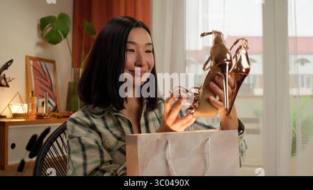 Aufgeregt glücklich asiatisch Koreanisch Frau Eröffnungspaket weibliche Einkäufe Rabatt Verkauf Käufer Kundenlieferung Geschenk neue modische Goldschuhe Stockfoto