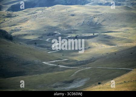 Aus der Vogelperspektive eine gewundene Straße im Herbsttal mit hellen Wolkenschatten vom Bjelasnica Peak in Bosnien und Herzegowina Stockfoto