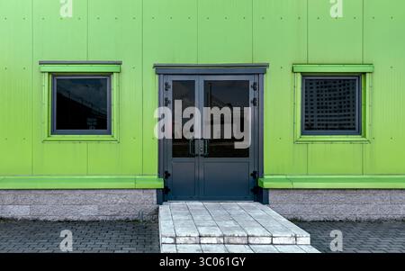 Eingang eines modernen Geschäfts- oder Industriegebäudes mit grün lackierten Metallpaneelen. Stockfoto