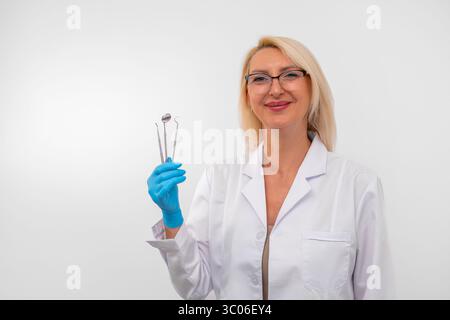Porträt einer selbstbewussten Zahnarztin mit Handschuhen und Instrumenten, einsatzbereit für den zahnärztlichen Eingriff. Gesundheitsfürsorge, Klinik und professionelles Versorgungskonzept Stockfoto