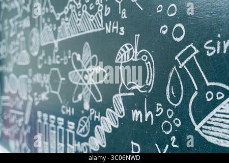 Nahaufnahme eines Schwarzen Bretts mit wissenschaftlichen Formeln, physikalischen Gleichungen, DNA-Struktur und chemischen Symbolen, die von Hand gezeichnet wurden. Bildung, Lernen und c Stockfoto