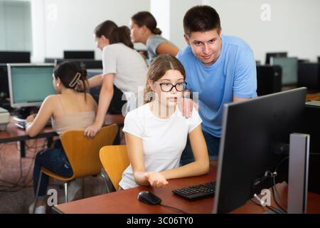 Teenager-Mädchen hilft Freundin, Probleme am Computer in der Schule zu lösen Stockfoto