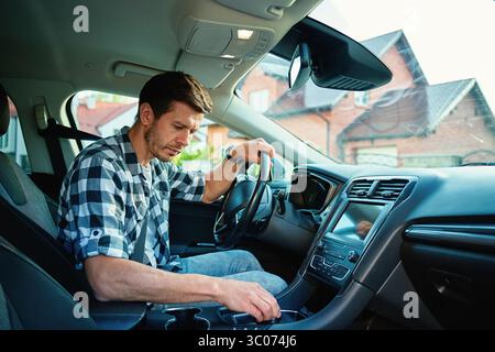 Mann, der in einem modernen Auto sitzt und den Gang mit Automatikgetriebe schaltet. Person, die sich auf das Fahren vorbereitet Stockfoto