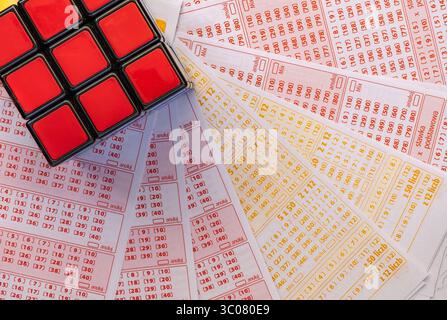 Glücksspiele, bunte Würfel, die über Lottoscheine in die Luft geworfen werden, sucht nach Zahlenspielen und Lotterien Stockfoto