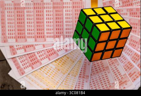 Glücksspiele, bunte Würfel, die über Lottoscheine in die Luft geworfen werden, sucht nach Zahlenspielen und Lotterien Stockfoto