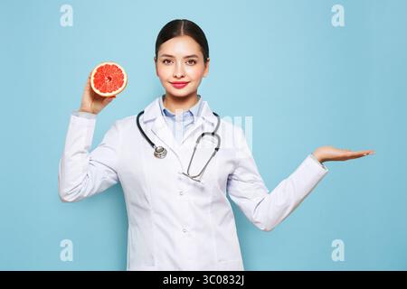 Porträt einer jungen Ärztin in einem medizinischen Mantel mit Grapefruit. Ernährung und gesunde Ernährung Stockfoto
