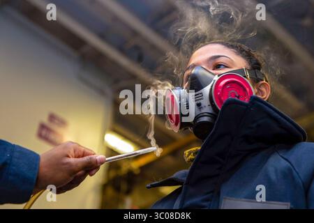 10. Oktober 2018 - Atlantik - Aviation Boatswains Mate (Handling) der Airman Noah Brooks ist während einer Evolution der Atemschutzausrüstung am 10. Oktober 2018 in der Hangarbucht des amphibischen Angriffsschiffs USS Iwo Jima (LHD 7) rauchreizend ausgesetzt. Iwo Jima ist vor der Teilnahme an Trident Junction 2018 im Gange, einer von der NATO geführten Übung zur Zertifizierung der NATO-Eingreiftruppen und zur Entwicklung der Interoperabilität zwischen den teilnehmenden NATO- und Partnerländern. (Kreditbild: © U.S. Navy/ZUMA Wire/ZUMAPRESS.com) Stockfoto