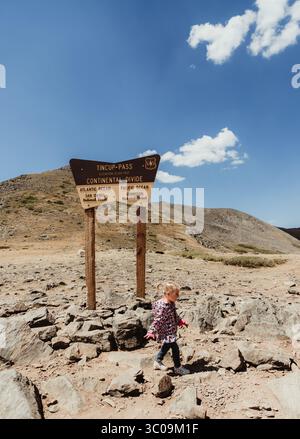 Kleinkind läuft vor dem TinCup Pass Continental Divide Schild Stockfoto