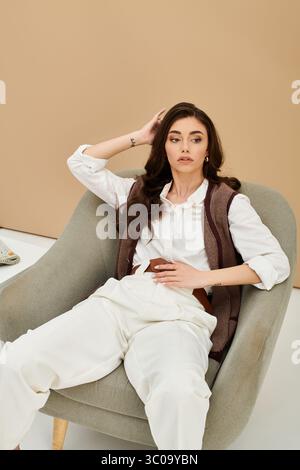 Eine stilvolle junge Frau sitzt anmutig in einem gemütlichen Stuhl und zeigt ihr schickes Outfit. Stockfoto
