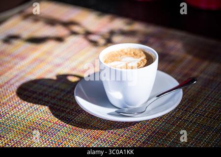 Schaumstoff Latte mit Schaumkunst im Morgenlicht Stockfoto
