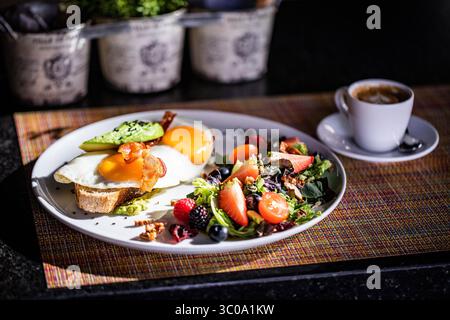Gesundes Frühstück mit gebratenem Ei auf Toast und Salat mit Obst Stockfoto