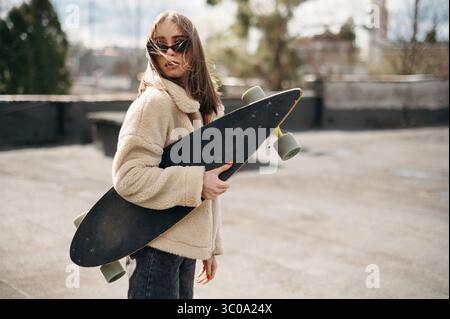 Junge Frau mit Skateboard auf dem Dach Stockfoto