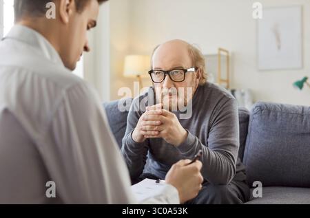 Junger Berufspsychologe, der ältere Patienten während der Therapiesitzung berät Stockfoto