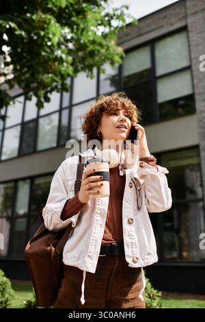 Weiße Jacke und Kopfhörer, verbindet sie sich mit jemandem, während sie in der Nähe ihres modernen Arbeitsplatzes schlendert. Stockfoto