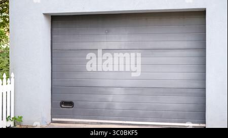 Ein modernes graues Garagentor aus nächster Nähe mit horizontalen Paneelen und einem schlanken, minimalistischen Design. Stockfoto