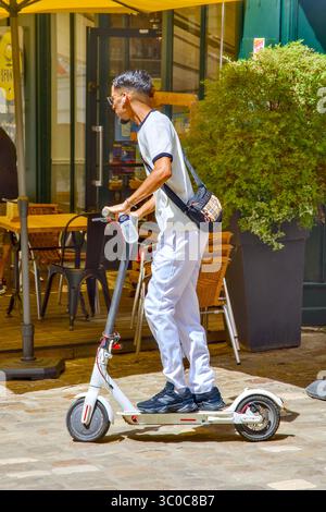Junger orientalischer Mann auf Elektroroller im Stadtzentrum - Loches, Indre-et-Loire (37), Frankreich. Stockfoto