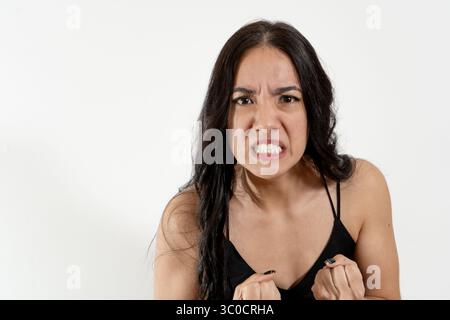 Studio-Porträt einer wütenden jungen Frau, die ihre Fäuste zusammendrückt und ihre Zähne zeigt Stockfoto