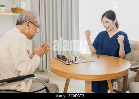 Asiatische Tochter und Großvater kümmern sich um und spielen gemeinsam Schach im Wohnzimmer zu Hause. alzheimer-Krankheit verhindern Stockfoto