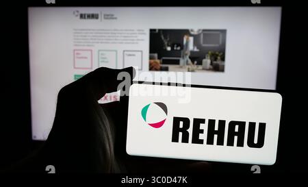Stuttgart, Deutschland - 17.05.2025: Person, die ein Mobiltelefon mit dem Logo des Kunststoffunternehmens Rehau Group auf dem Bildschirm vor der Webseite hält. Stockfoto