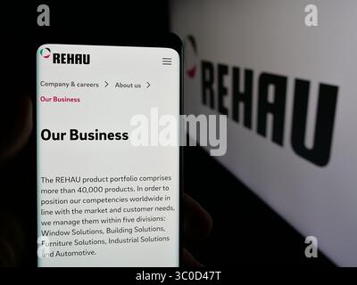 Stuttgart, Deutschland - 17.05.2025: Handybesitzer mit Webseite des Kunststoffunternehmens Rehau Group auf dem Bildschirm vor dem Logo. Stockfoto