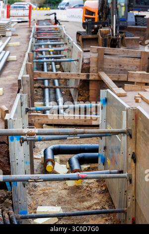 Neue moderne, isolierte städtische Rohrleitungsbaustelle freiliegende unterirdische Rohre in Unterwassergräben. Isolierte Stahlrohre liegen an Stockfoto