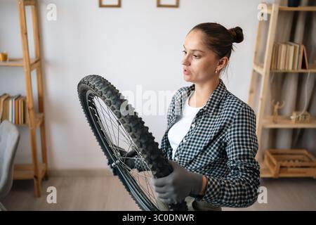 Eine junge Frau repariert ihr Fahrrad im Wohnzimmer zu Hause Stockfoto
