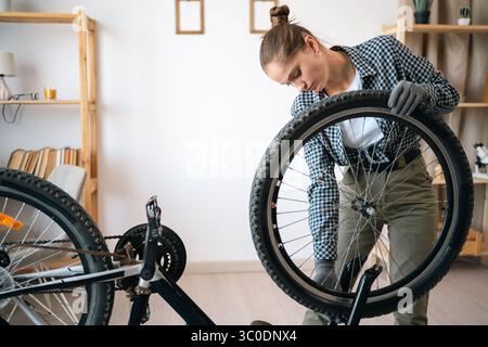 Eine junge Frau repariert und wartet ihr Fahrrad zu Hause Stockfoto