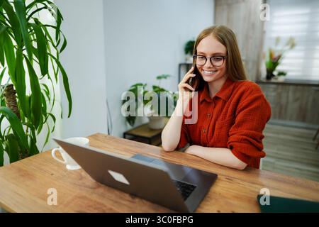 Lächelnder Mitarbeiter, der von zu Hause aus telefoniert Stockfoto