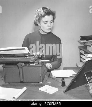 Büromädchen in den 1950ern Eine Frau sitzt vor ihrer Schreibmaschine und schaut den Text auf dem Blatt neben ihr an und schreibt den Text auf der Schreibmaschine. Sie ist schön gekleidet und macht einen ernsthaften Eindruck. Schweden 1954.Foto Kristoffersson BO24-9 Stockfoto