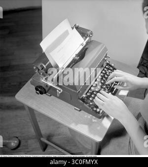 Büromädchen in den 1950ern Eine Frau sitzt an einem Schreibtisch und tippt auf ihre Schreibmaschine. 1950. Stockfoto