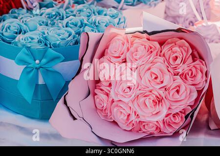 Pinkfarbene Rosen und blaue Rosen an der Box schaffen ein schönes künstliches Blumenarrangement zum Schenken oder Dekorieren Stockfoto