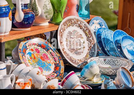 1. Juni 2025, Belgrad, Serbien: Bunte Tassen aus Vintage Porzellan, Teller, Teekannen und Vasen auf einem Holzstand auf einem Flohmarkt Stockfoto