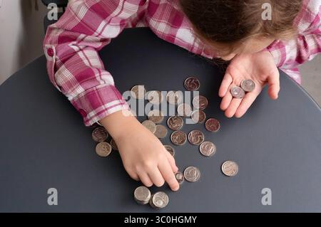 Hände eines Kindes mit Münzen auf grauem Hintergrund, Nahaufnahme Stockfoto