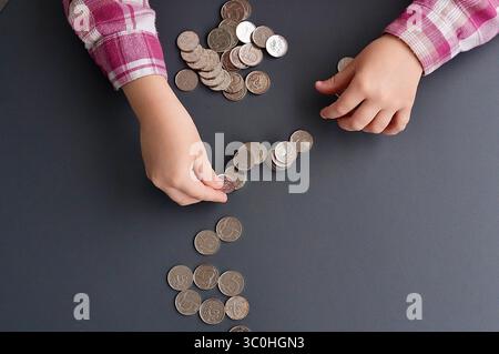 Hände eines Kindes mit Münzen auf grauem Hintergrund, Nahaufnahme Stockfoto