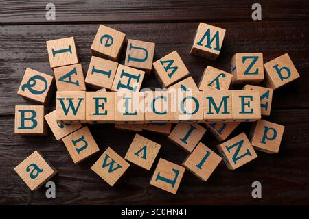 Word Welcome aus Holzwürfeln auf dem Tisch, Blick von oben Stockfoto