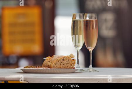 Elegante Gläser Sekt mit handwerklichem Brot im Freien, die das entspannte Ambiente des Essens im Freien und des geselligen Genusses während des Tages einfangen Stockfoto