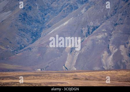 Eine riesige Landschaft mit zerklüfteten Bergen mit trockenen, felsigen Hängen und karger Vegetation. Das Gelände zeichnet sich durch Erdtöne und ein Gefühl von aus Stockfoto