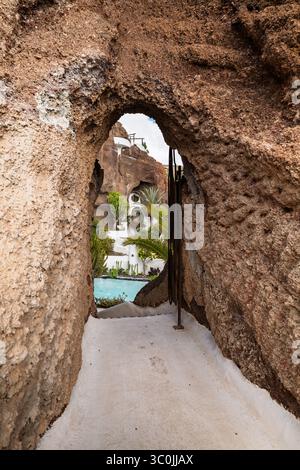 Eine atemberaubende weiße Villa mit einem Pool, eingebettet zwischen roten vulkanischen Felsen, harmonisch in die dramatische natürliche Landschaft der Insel. Stockfoto