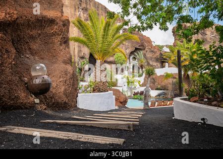 Eine atemberaubende weiße Villa mit einem Pool, eingebettet zwischen roten vulkanischen Felsen, harmonisch in die dramatische natürliche Landschaft der Insel. Stockfoto