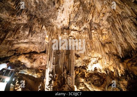 Besucher bestaunen die komplizierten Formationen von Stalaktiten und Stalagmiten in den atemberaubenden Höhlen von Malaga, Spanien. Die natürliche Schönheit wird noch verstärkt Stockfoto