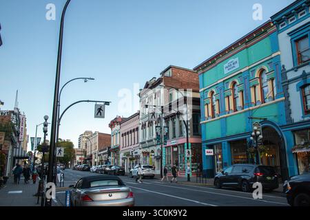 Victoria, BC, KANADA - Juni 30 2024 : Abendblick auf das historische Paper Box Building in der Innenstadt von Victoria und die umliegenden farbenfrohen Fassaden, Geschäfte, Autos, an Stockfoto