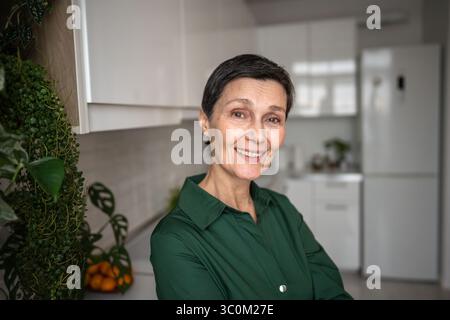 Fröhliche reife Frau lächelt glücklich in die Kamera zu Hause, natürliches Ich. Selbstakzeptanz Stockfoto