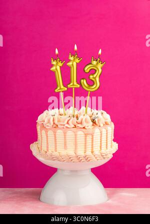 Nummer 113 Geburtstagskerze - rosafarbener Festkuchen mit Tropfguss Stockfoto