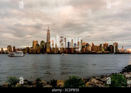 Jersey City, NJ - USA - 19. Juli 2025 Ein Panoramablick auf Lower Manhattan leuchtet in goldenen Sonnenuntergang, von Liberty State P aus über den Hudson River Stockfoto
