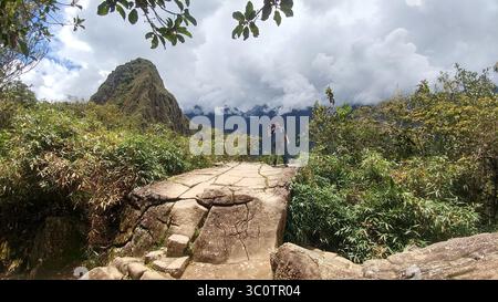 Ein erwachsener dunkelhäutiger Latino-Fotograf fotografiert die archäologische Stätte Machu Picchu, eines der sieben Weltwunder Stockfoto
